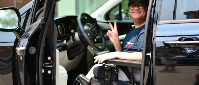RJ poses in the drivers seat of a car.