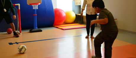 Boy shooting a soccer ball into a net in a gym