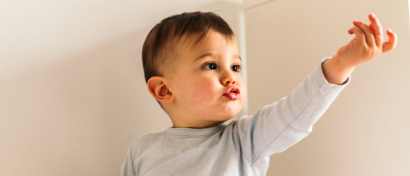 A toddler is pursing their lips with an outstretched arm.