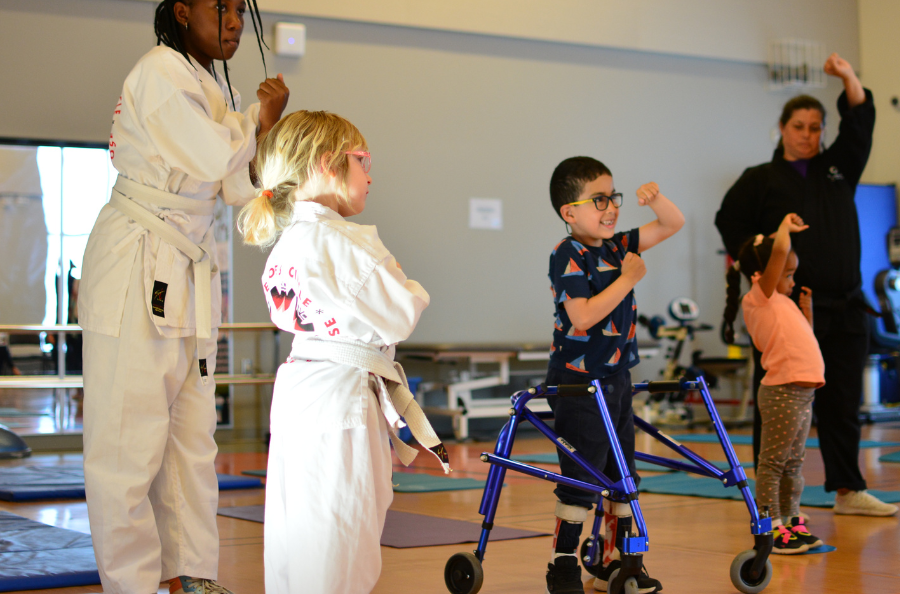 Three children accompanied by two adult learning karate.