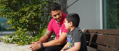 Man sitting on bench looking at child seated next to him