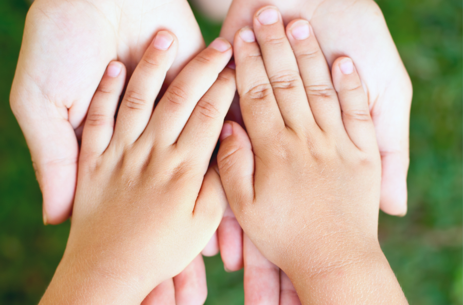 A child's hands, inside the palm of an adults hands.