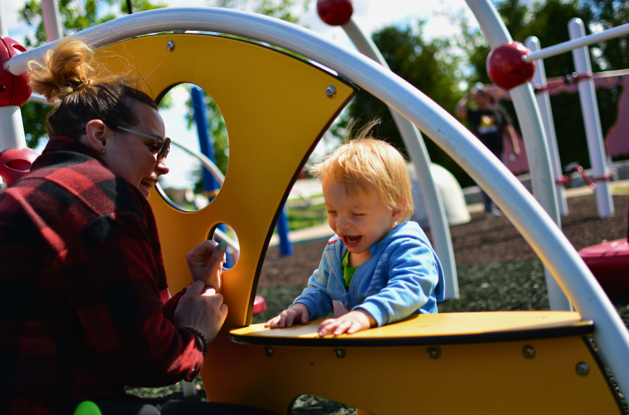 A child playing at the park with his mom. 