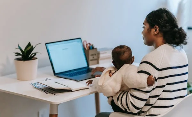 A mother with her young child on a laptop at her desk