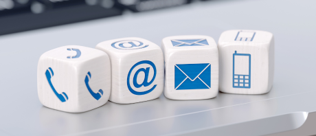 Four dice each with an icon - a telephone, the @ symbol, envelope and cell phone.