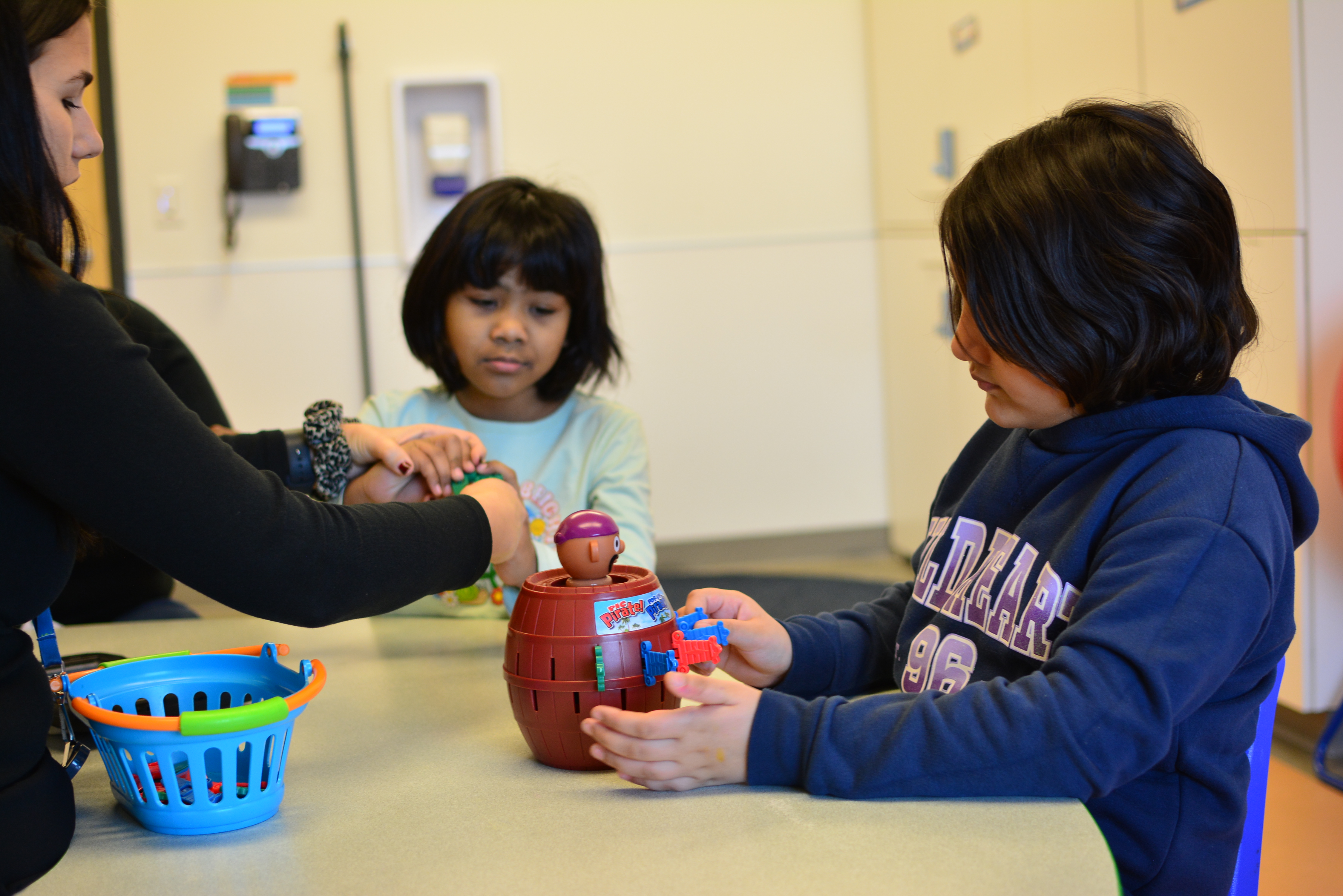 Two ABA students play pop-up pirate, facilitated by a clinician.