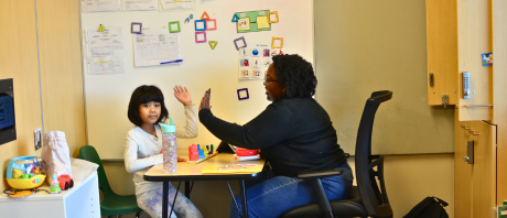 A child and therapist high-five.