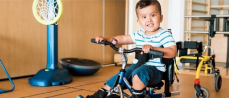 A toddler riding a bike in at ErinoakKids' gymnasium