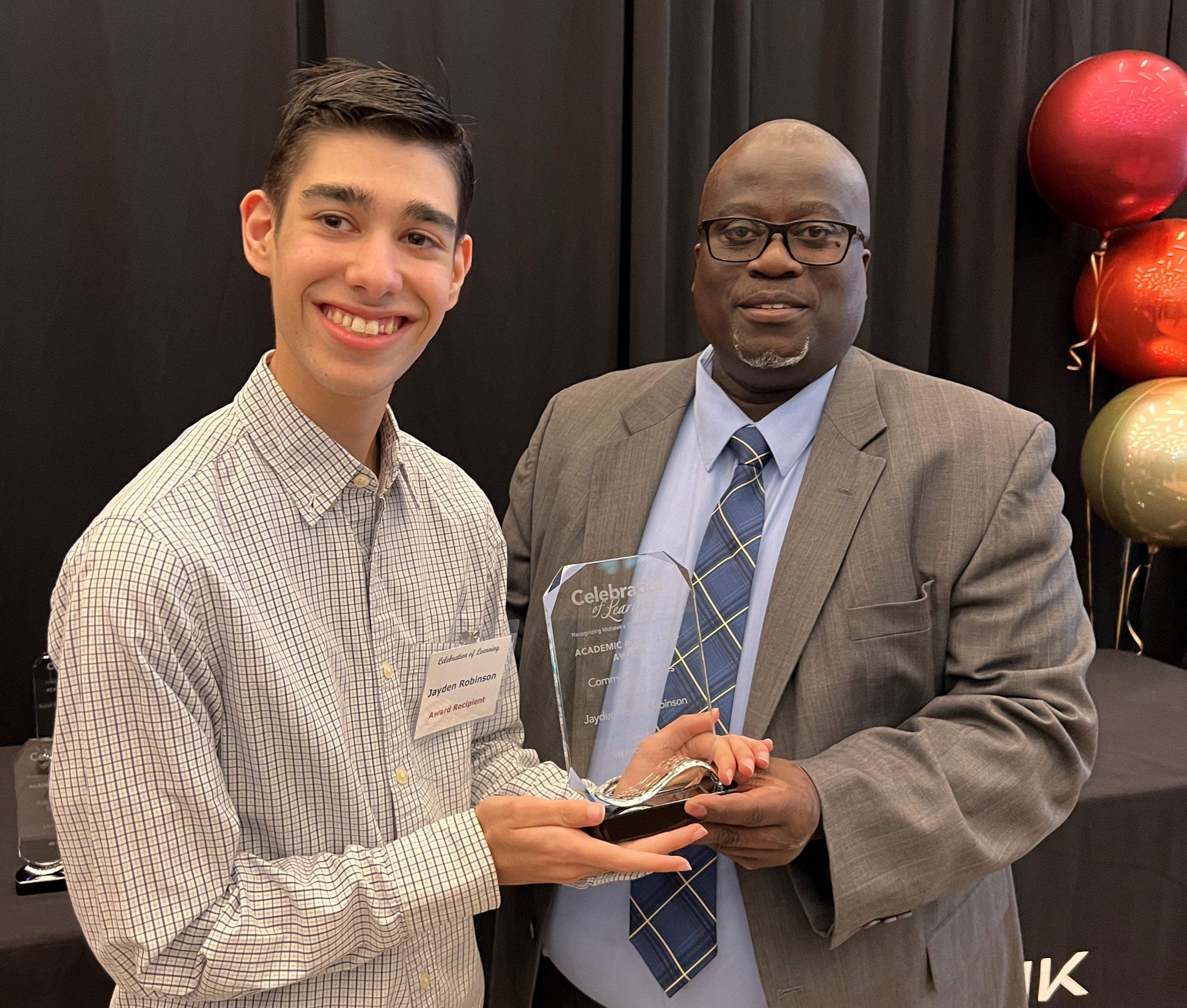 Jayden posing with Cebert Adamson, VP of Academics at Mohawk College, holding the plaque for the Academic Excellence Award