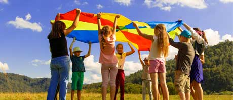 Children outside playing with a colourful parachute